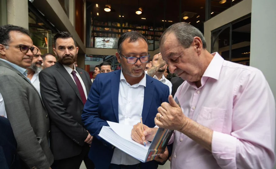 Senador Omar Aziz assina documento durante coletiva em Manaus ao lado de lideranças políticas, em evento de anúncio da pré-candidatura ao Governo do Amazonas e apresentação de plano estratégico para as eleições de 2026.